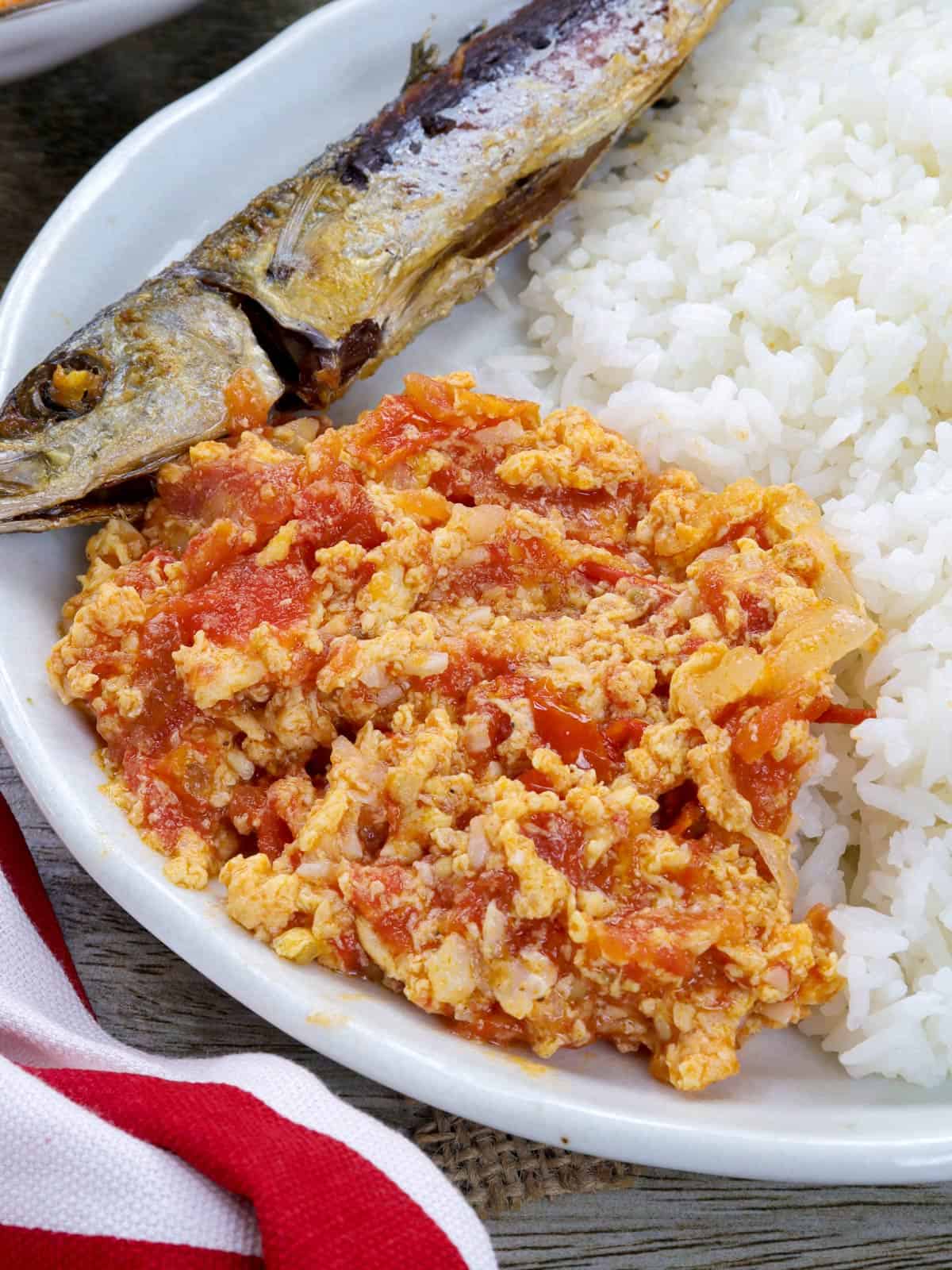 ginisang kamatis at itlog with rice and fried galunggong on a white plate.