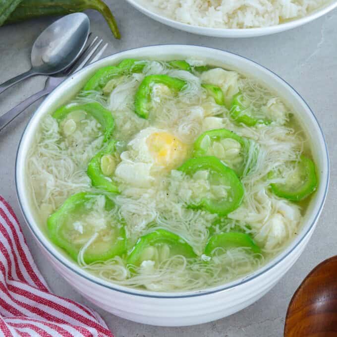 Miswang Ebun with Patola in a white bowl with a plate of steamed rice in the background.