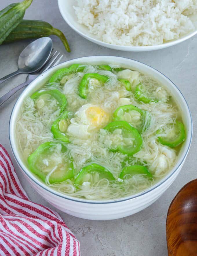 Miswang Ebun with Patola in a white bowl with a plate of steamed rice in the background.