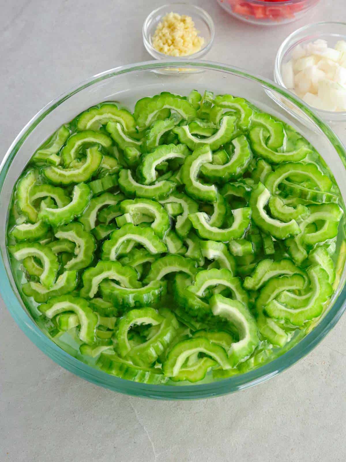 sliced ampalaya soaking in a bowl of water.