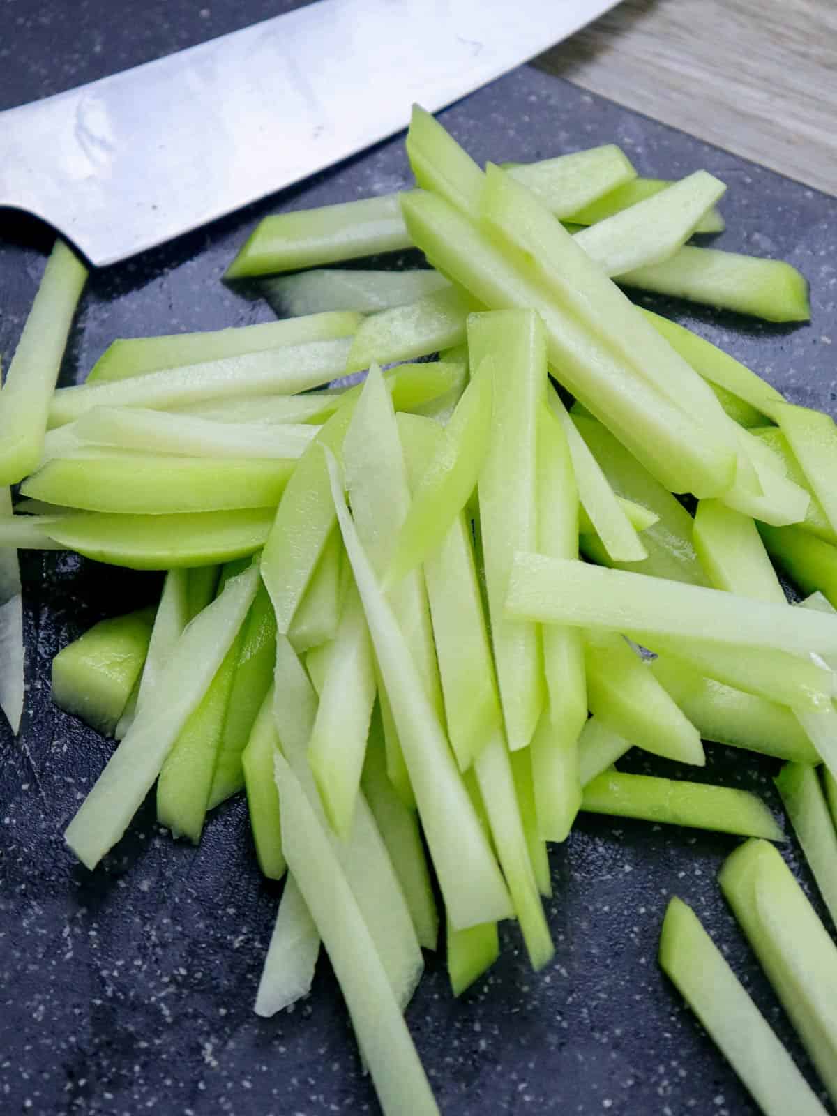 sayote cut into thin stirps on a cutting board.