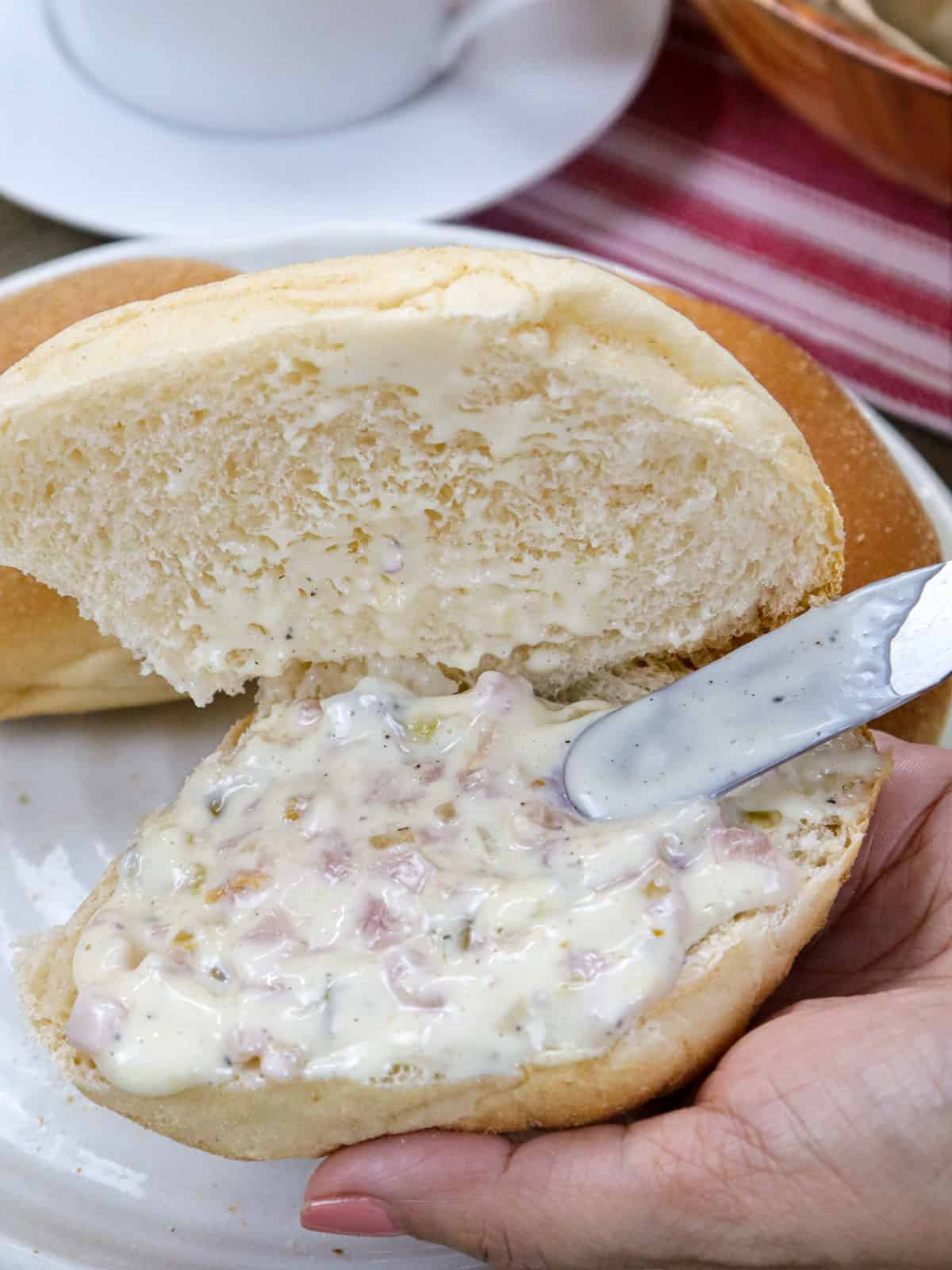 spreading ham sandwich spread on pandesal.