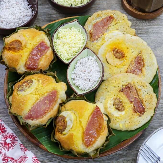 oven baked bibingka and bibingka pancakes on a banana lined platter with shredded cheese and grated coconut on the side.