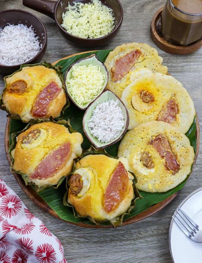 oven baked bibingka and bibingka pancakes on a banana lined platter with shredded cheese and grated coconut on the side.