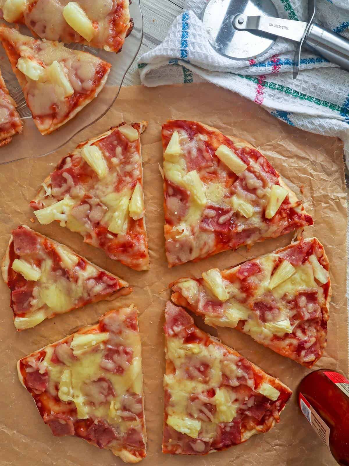 sliced Hawaiian Pizza on brown paper.